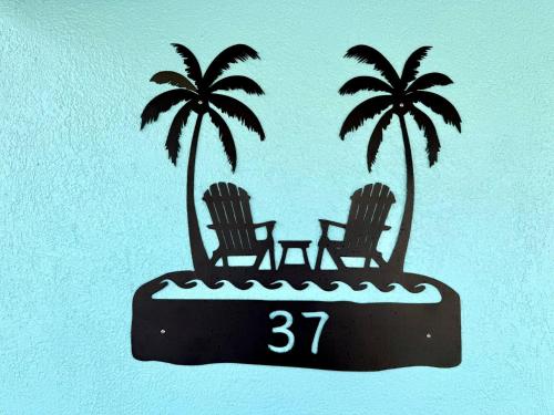 two chairs and palm trees on an island with the number at ZenBreak Steps to the Sea 2Bd in Saint Peter