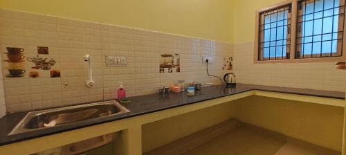 a kitchen counter with a sink and a window at Feel Home Stay in Urapakkam