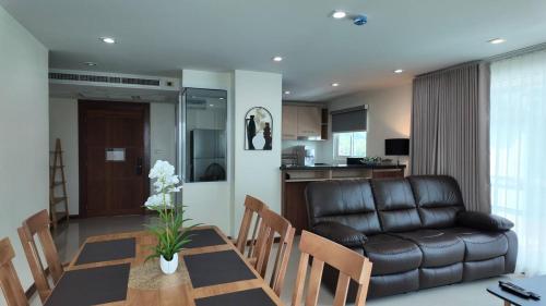 a living room with a table and a leather couch at Kashouse hatyai in Ban Khlong Pleo