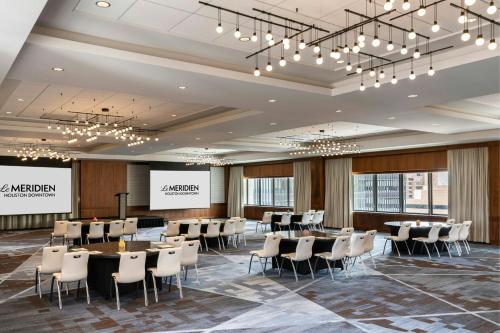 a conference room with tables and chairs and a projection screen at Le Meridien Houston Downtown in Houston