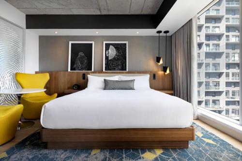 a bedroom with a large bed and a yellow chair at Humaniti Hotel Montreal, Autograph Collection in Montréal
