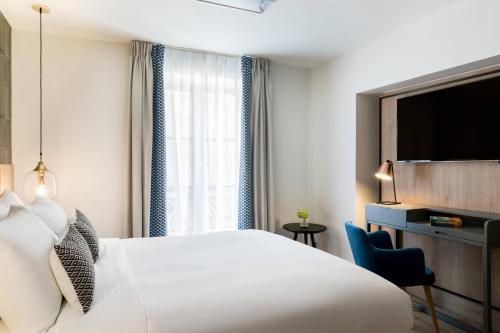 a hotel room with a white bed and a television at Renaissance Paris Vendome Hotel in Paris