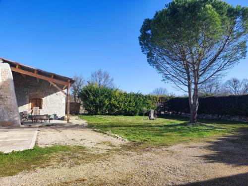 un arbre assis à côté d'un bâtiment en pierre dans l'établissement La tourterelle, à Cayriech