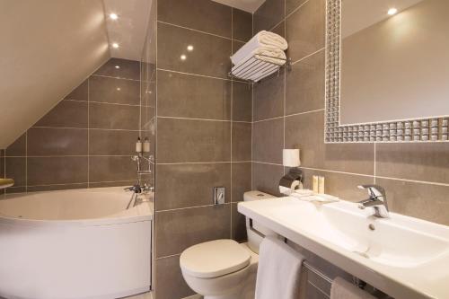 a bathroom with a toilet and a sink and a tub at Hotel Best Western Anjou Lafayette in Paris