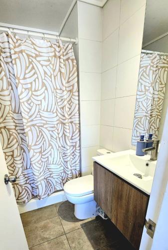 a bathroom with a shower curtain and a toilet at Depto Apart Hotel Atenea Centro Temuco in Temuco