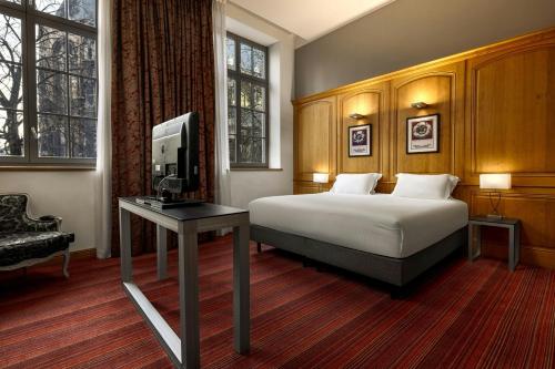 a bedroom with a bed and a tv and a table at Hôtel de Bourgtheroulde, Autograph Collection in Rouen