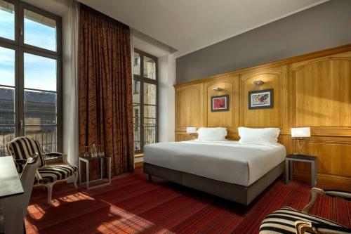 a hotel room with a bed and a large window at Hôtel de Bourgtheroulde, Autograph Collection in Rouen