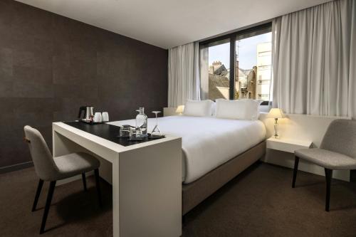 a hotel room with a bed and a desk and chairs at Hôtel de Bourgtheroulde, Autograph Collection in Rouen