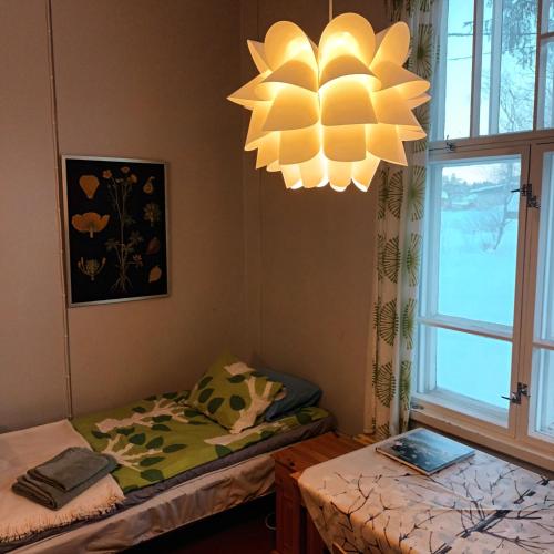 a room with two beds and a chandelier at Kukkolan vanha koulu in Kukkola