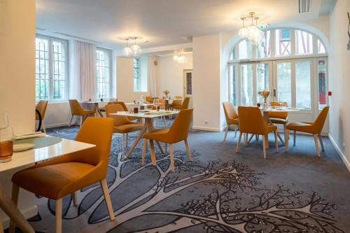 a dining room with tables and chairs and windows at Hôtel de Bourgtheroulde, Autograph Collection in Rouen