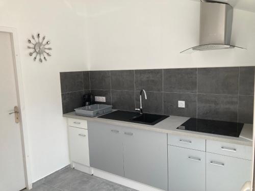 une cuisine avec des armoires blanches et un évier dans l'établissement Aux Portes du Grand Bleu, à Grosbreuil