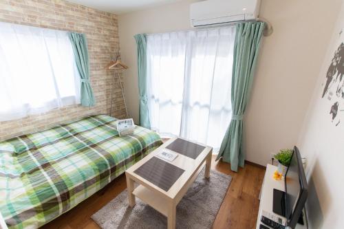 a small bedroom with a bed and a table and window at 所沢駅徒歩10分の閑静なワンルーム ベルーナドーム 東京 川越観光拠点に コンビニ徒歩3分 in Tokorozawa
