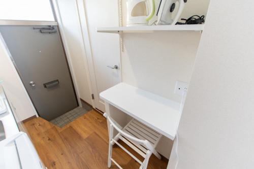 a white desk in a small room with a door at 所沢駅徒歩10分の閑静なワンルーム ベルーナドーム 東京 川越観光拠点に コンビニ徒歩3分 in Tokorozawa