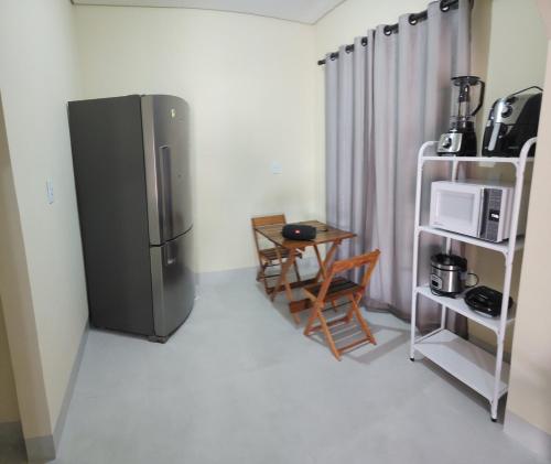 a kitchen with a refrigerator and a table and a microwave at Casa nova completa, proximo a UFR in Rondonópolis