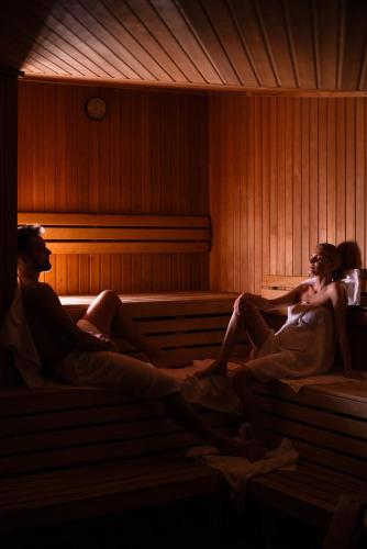 a couple of people sitting in a sauna at Młyn Jacka Hotel & Spa in Wadowice