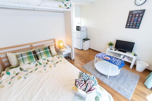 a bedroom with a bed and a desk and a television at 所沢駅徒歩10分の閑静なワンルーム ベルーナドーム 東京 川越観光拠点に コンビニ徒歩3分 in Tokorozawa