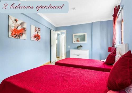 a bedroom with two beds with red sheets and blue walls at Luxury Apartaments in Costa Adeje, Los Geranois in Adeje