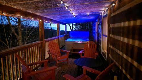a porch with chairs and a hot tub and lights at Rustic Cabin in Sevierville