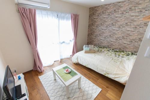 a bedroom with a brick wall and a bed and a table at 所沢駅徒歩10分の閑静なワンルーム ベルーナドーム 東京 川越観光拠点に コンビニ徒歩3分 in Tokorozawa
