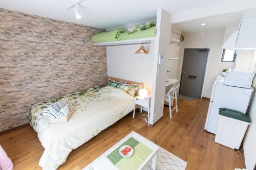 a bedroom with a bed and a brick wall at 所沢駅徒歩10分の閑静なワンルーム ベルーナドーム 東京 川越観光拠点に コンビニ徒歩3分 in Tokorozawa