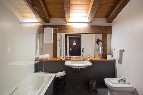 a bathroom with a sink and a tub and a toilet at Hotel Dolarea in Beasain