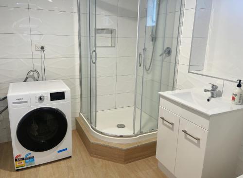 y baño con ducha y lavadora. en Living Oasis, en Auckland