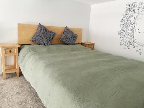 1 dormitorio con 1 cama verde grande y 2 almohadas en Living Oasis, en Auckland