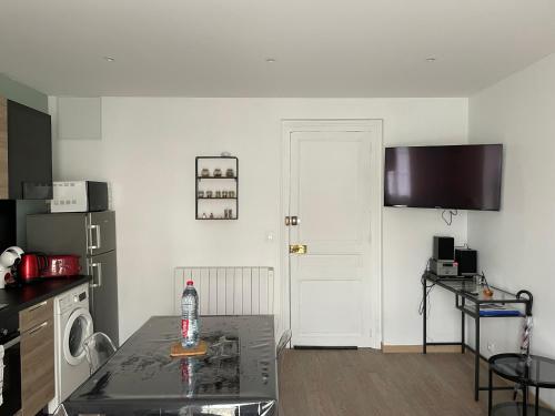 a kitchen with a refrigerator and a table in a room at Meublé 42 m2 à Vittel proche Thermes-SPA in Vittel