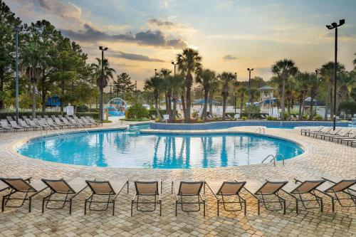 a large swimming pool with chairs and palm trees at Sheraton Broadway Resort Villas in Myrtle Beach