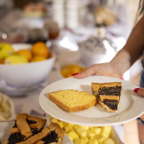 a person holding a plate with two slices of cake at Tenuta Santicuti in Acaya