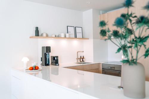 a white kitchen with a vase of flowers on a counter at clea flims - wandern, biken und stilvoll entspannen in Flims