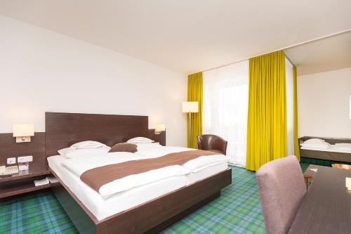 a hotel room with a large bed and a desk at Hotel Alpenhof Postillion in Kochel