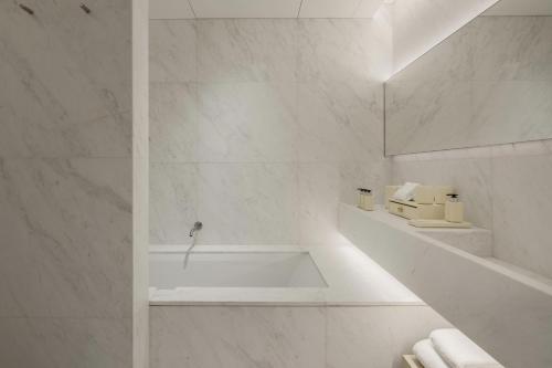 a white bathroom with a tub and a sink at Duxton Reserve Singapore, Autograph Collection in Singapore