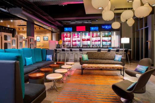 a bar with couches and chairs in a room at Aloft Hotel Rogers Bentonville in Rogers