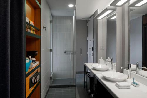 a bathroom with two sinks and a shower at Aloft Hotel Rogers Bentonville in Rogers