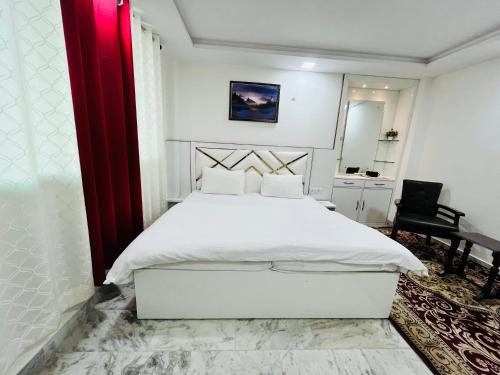 a bedroom with a white bed and a red curtain at Alibaba’s Indiana Homestay in Agra