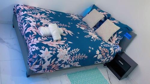 - un lit bleu avec un oreiller à motifs floraux et un rouleau de papier dans l'établissement OT Appart City Logement élégant et central, à Clermont-Ferrand