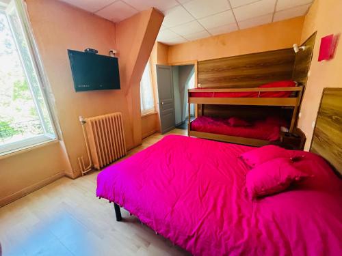 une chambre avec un grand lit avec une couverture rose dans l'établissement F1 Drosera, à La Bourboule