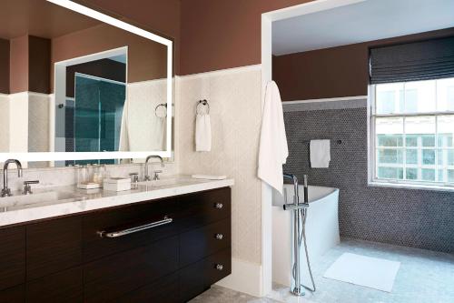 a bathroom with a sink and a tub and a mirror at The Mayflower Hotel, Autograph Collection in Washington