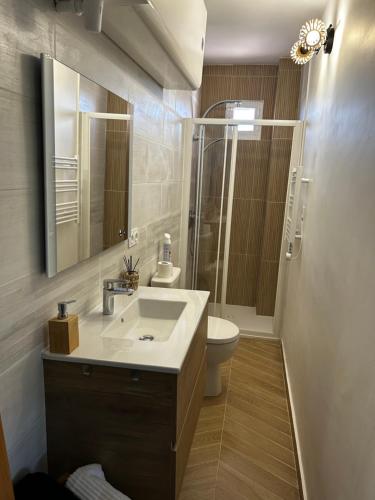 une salle de bain avec un lavabo, des toilettes et un miroir dans l'établissement Le Namasté, à La Ciotat