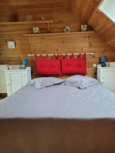 une chambre avec un grand lit avec des oreillers rouges dans l'établissement GITE LES MOUETTES MAISON A 300m de la MER, à Pirou