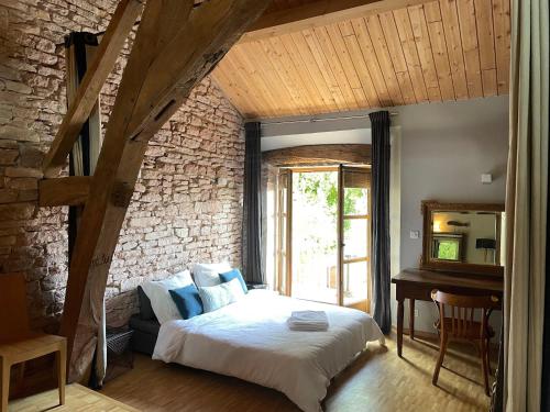 - une chambre avec un lit dans une pièce dotée d'un mur en briques dans l'établissement Gîte Le Clos de Miribel, à Givry