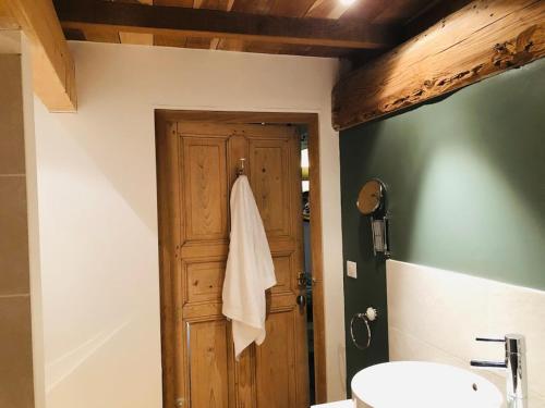 La salle de bains est pourvue d'une porte en bois et d'un lavabo. dans l'établissement Gîte Le Clos de Miribel, à Givry