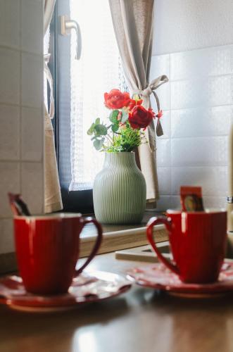 a table with two cups and a vase with flowers at Hauptman apartman in Nagyatád