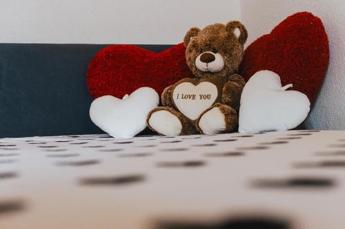 a teddy bear sitting in front of two hearts at Hauptman apartman in Nagyatád