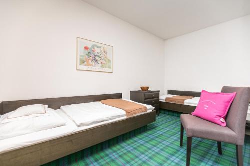 two beds and a chair in a room at Hotel Alpenhof Postillion in Kochel