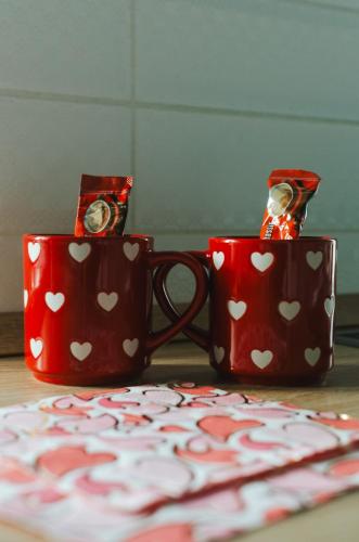 two red mugs with hearts on them sitting on a table at Hauptman apartman in Nagyatád