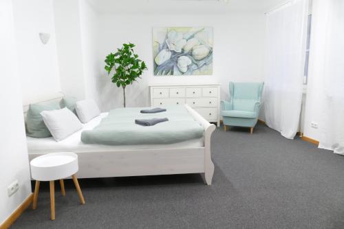 a bedroom with a white bed and a blue chair at Innenstadt - 110m2 wunderschöner Altbau am Landesmuseum mit 3 Schlafzimmern und 2 Bädern in Greifswald
