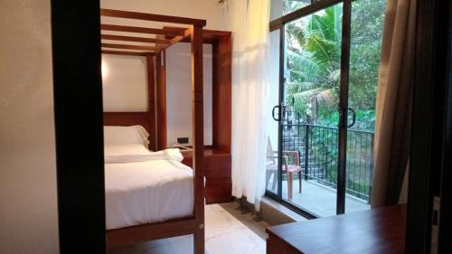 een slaapkamer met een bed en een groot raam bij Surftunnel Beach Resort in Weligama