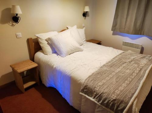 une chambre avec un grand lit avec des draps et des oreillers blancs dans l'établissement Superbe T2 classé 3 étoiles bien situé, à Villarembert